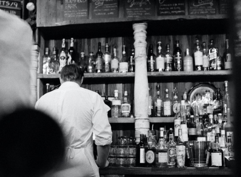 zwart wit foto van kelner voor bar