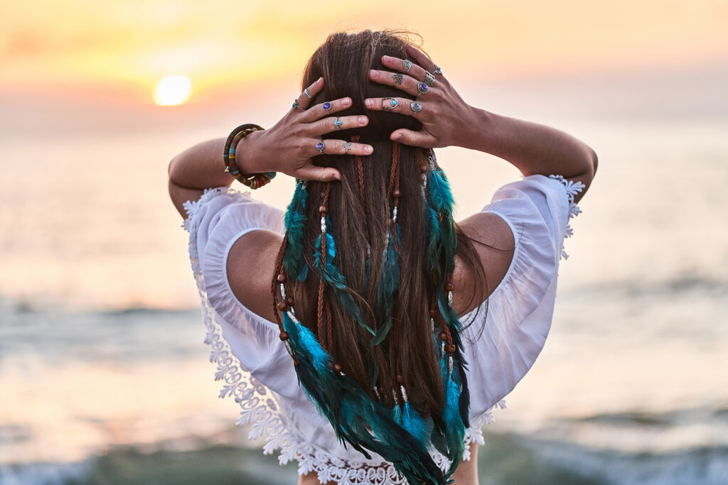Vrouw met veren in het haar bij zonsondergang — spirituele en holistische lifestyle